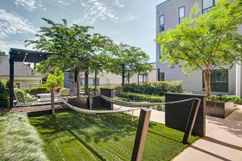 a yard with a hammock and trees and a building